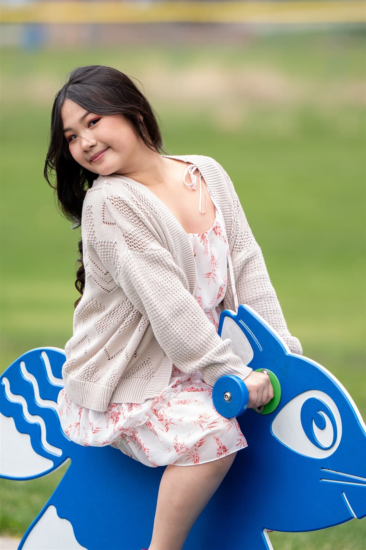 Portrait sitting on a playground figure in a park.