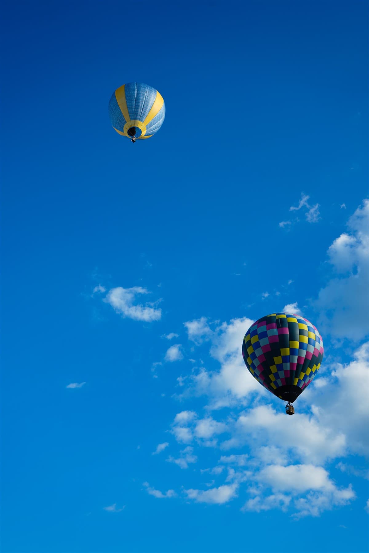 Hot air balloons drifting near a break in the clouds.