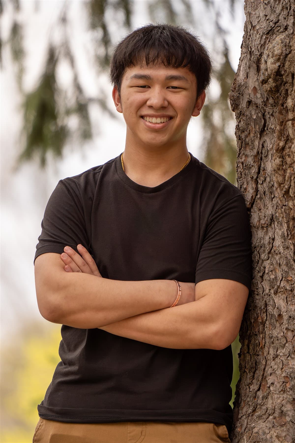 Portrait leaning against a tree outdoors.