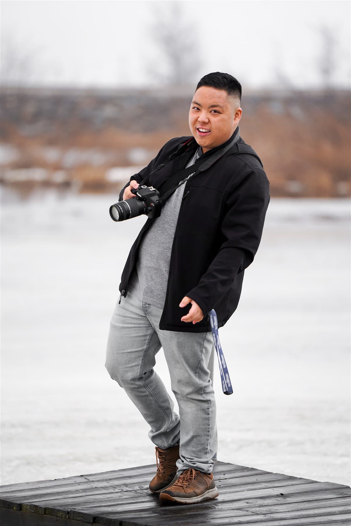 Portrait standing on a boardwalk near the water.