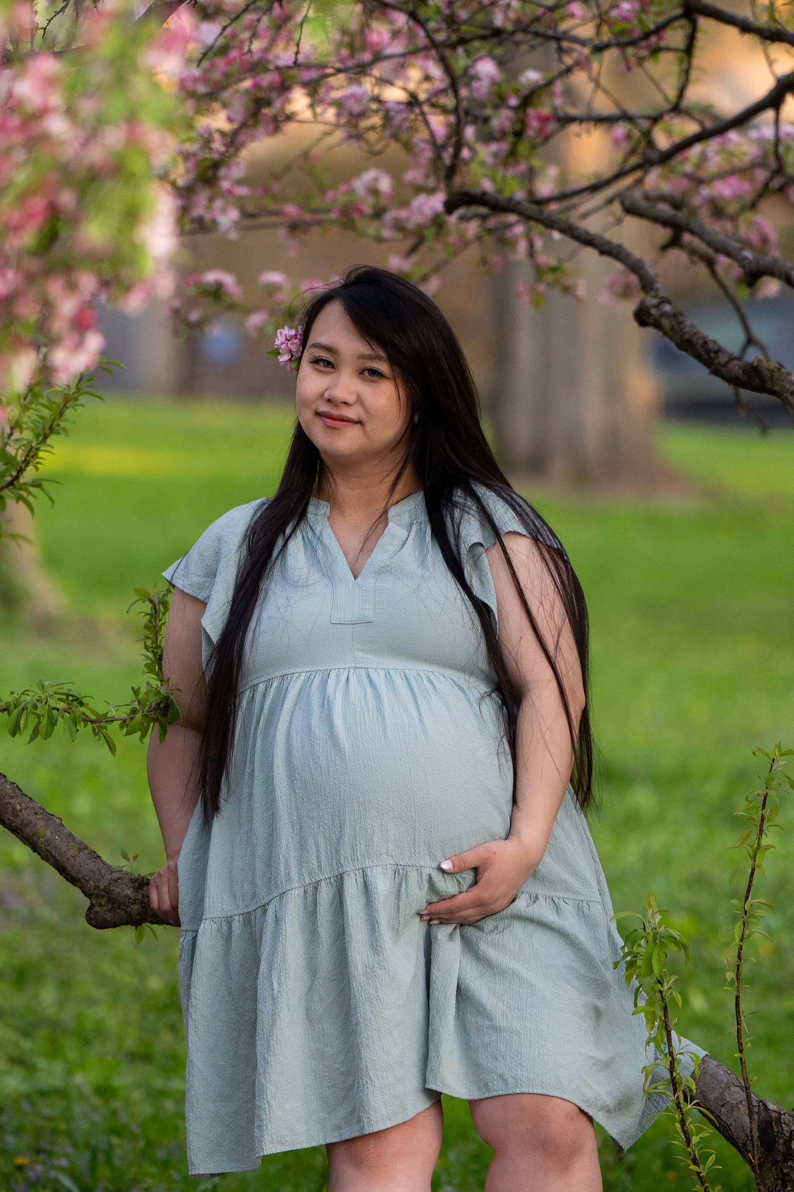 Standing portrait under pink flowering branches.