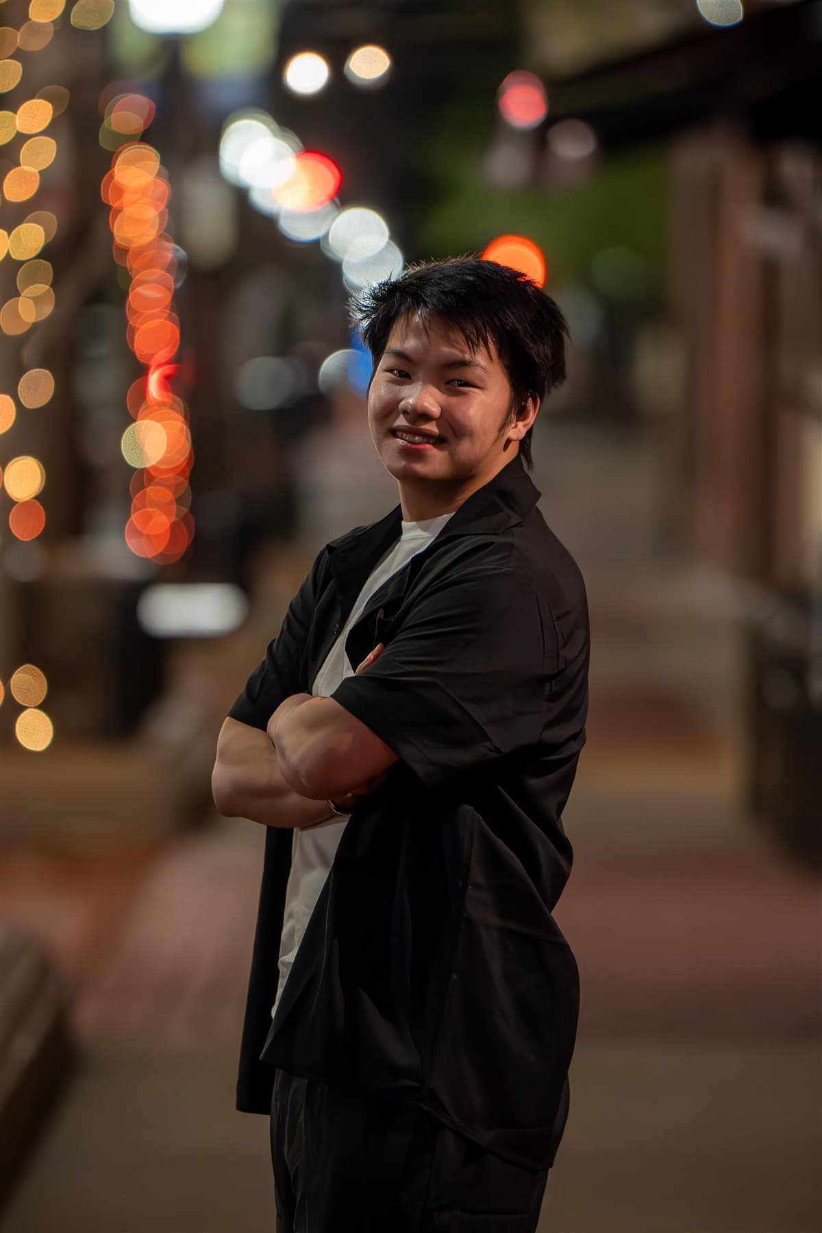 Portrait at night with soft city lights in the background.