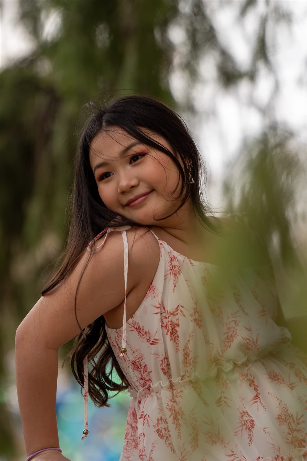 Portrait framed by soft foreground greenery.